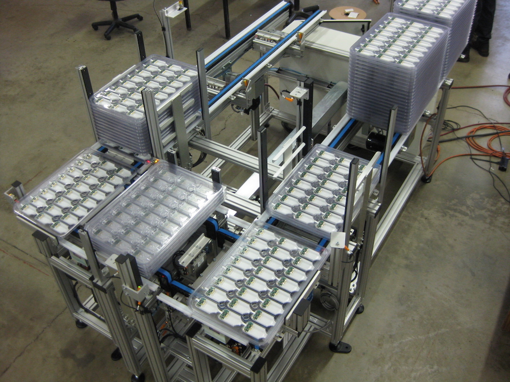 Stackable trays on pallet conveyor